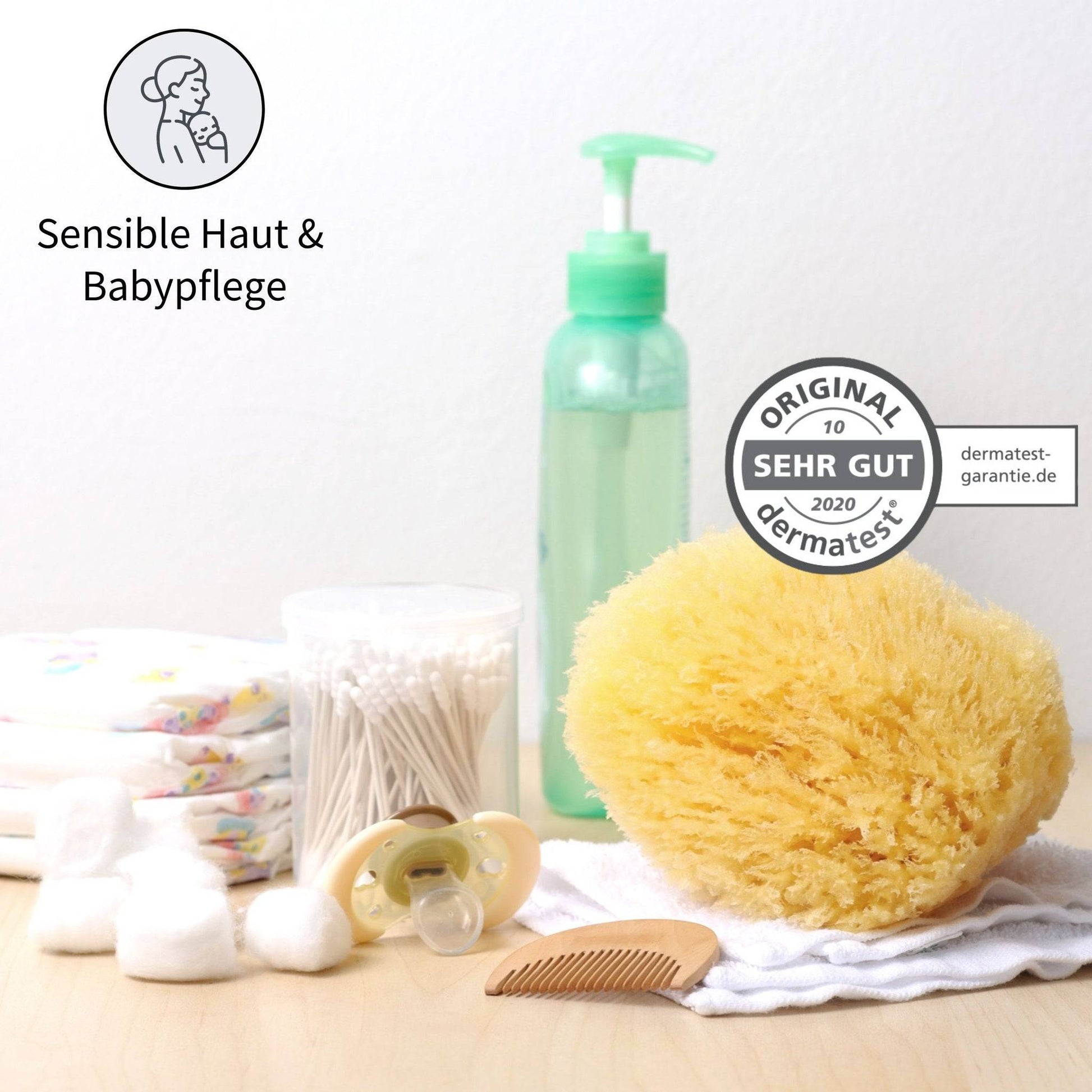 Baby Naturschwamm zur sanften Pflege sensibler Haut mit Dermatest-Siegel, umgeben von Babyartikeln wie Windeln, Wattepads und Pflegeflasche