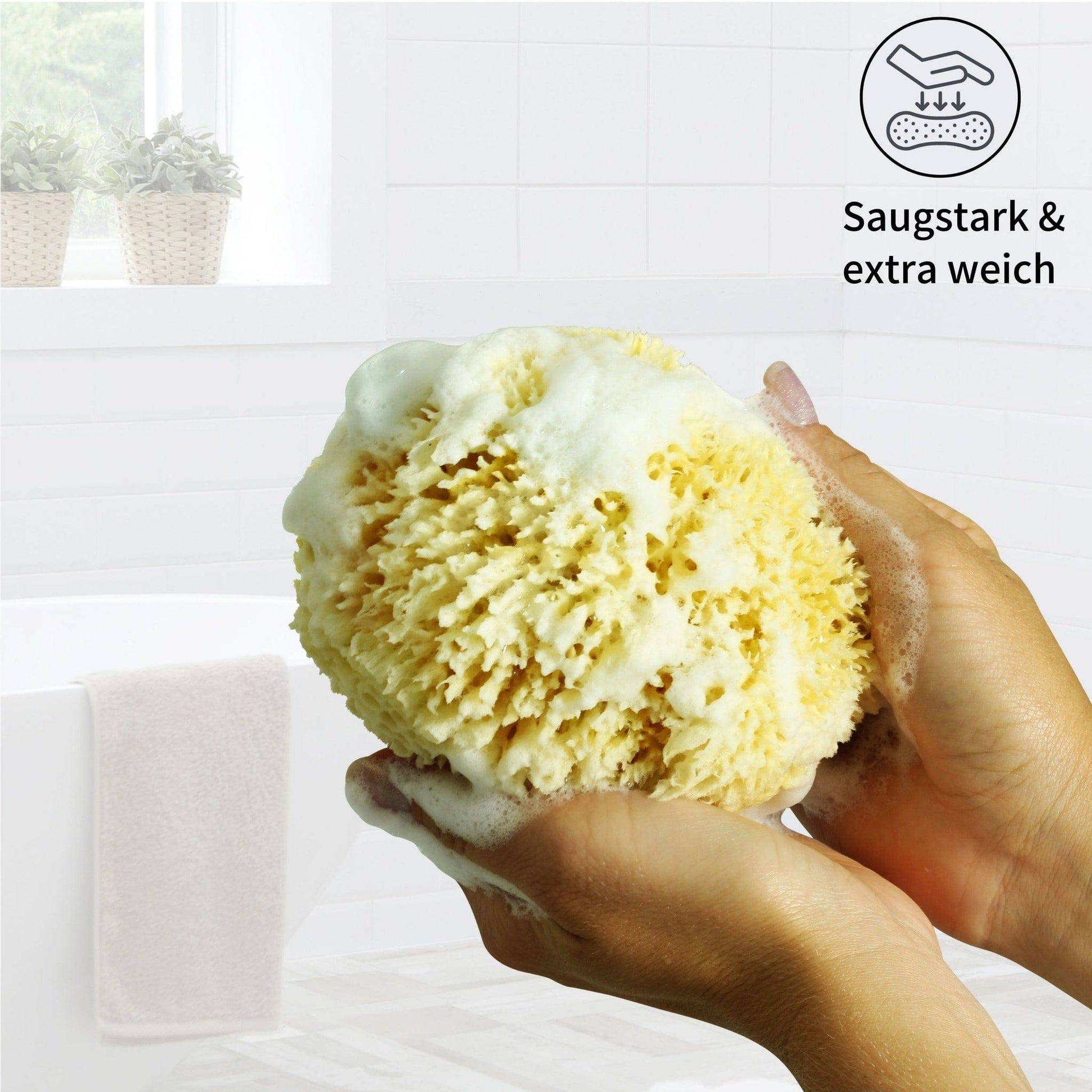 Naturschwamm als Duschschwamm in der Hand mit viel Schaum für sanfte Körperreinigung unter der Dusche