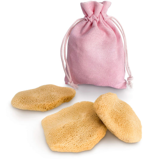 Drei flache Gesichtsschwämme aus Naturschwamm mit rosa Baumwollbeutel auf weißem Hintergrund