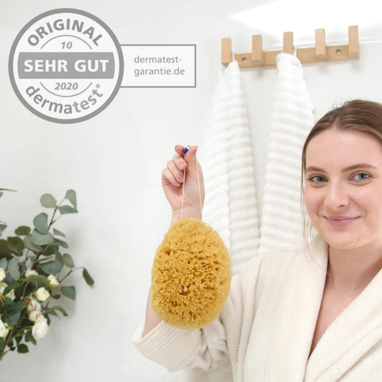 Frau hält natürlichen Duschschwamm mit Dermatest-Siegel – hautfreundlich und ideal für empfindliche Haut